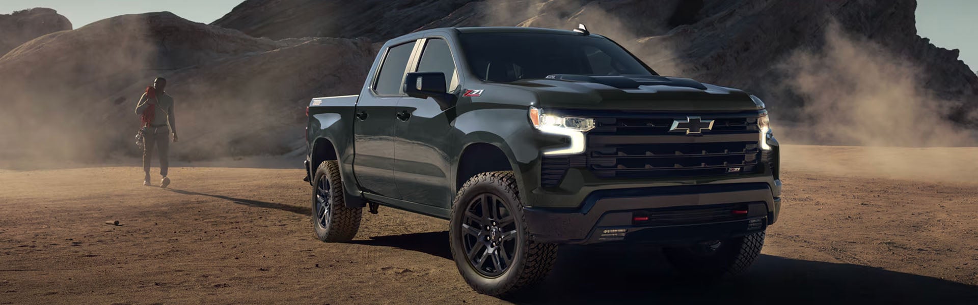 Black Chevrolet Silverado truck off-roading in desert terrain.