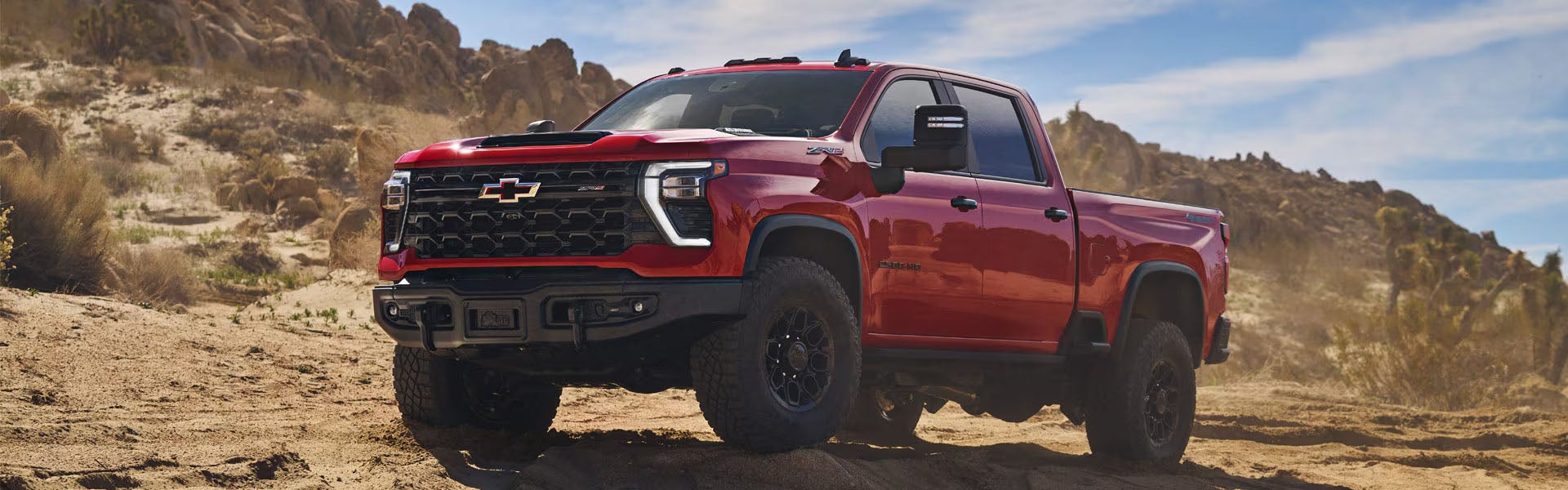 Red Chevrolet Silverado 3500 HD on an off-road trail.